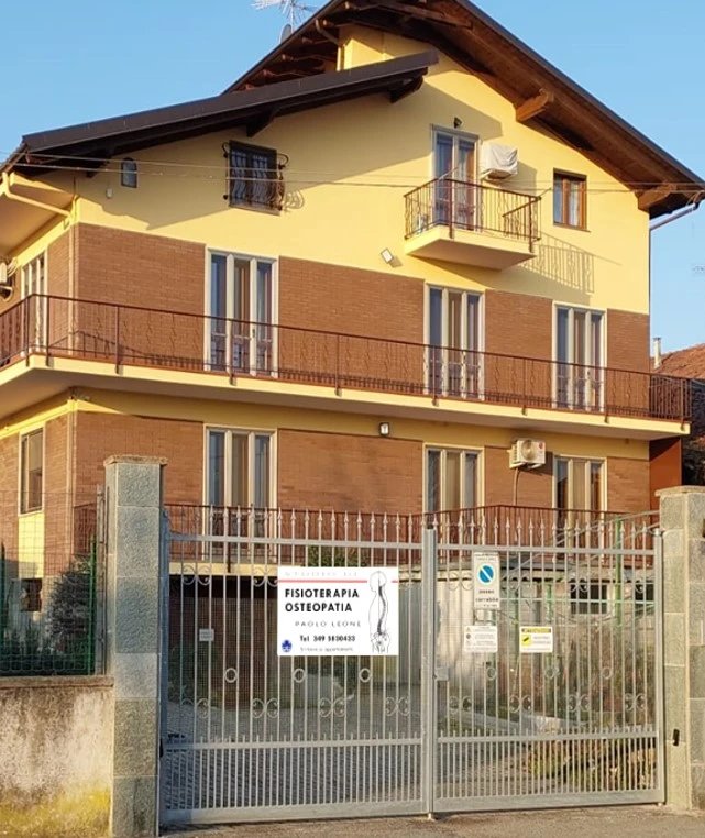 L'esterno dello studio, con il cartello Fisioterapia Osteopatia sul cancello